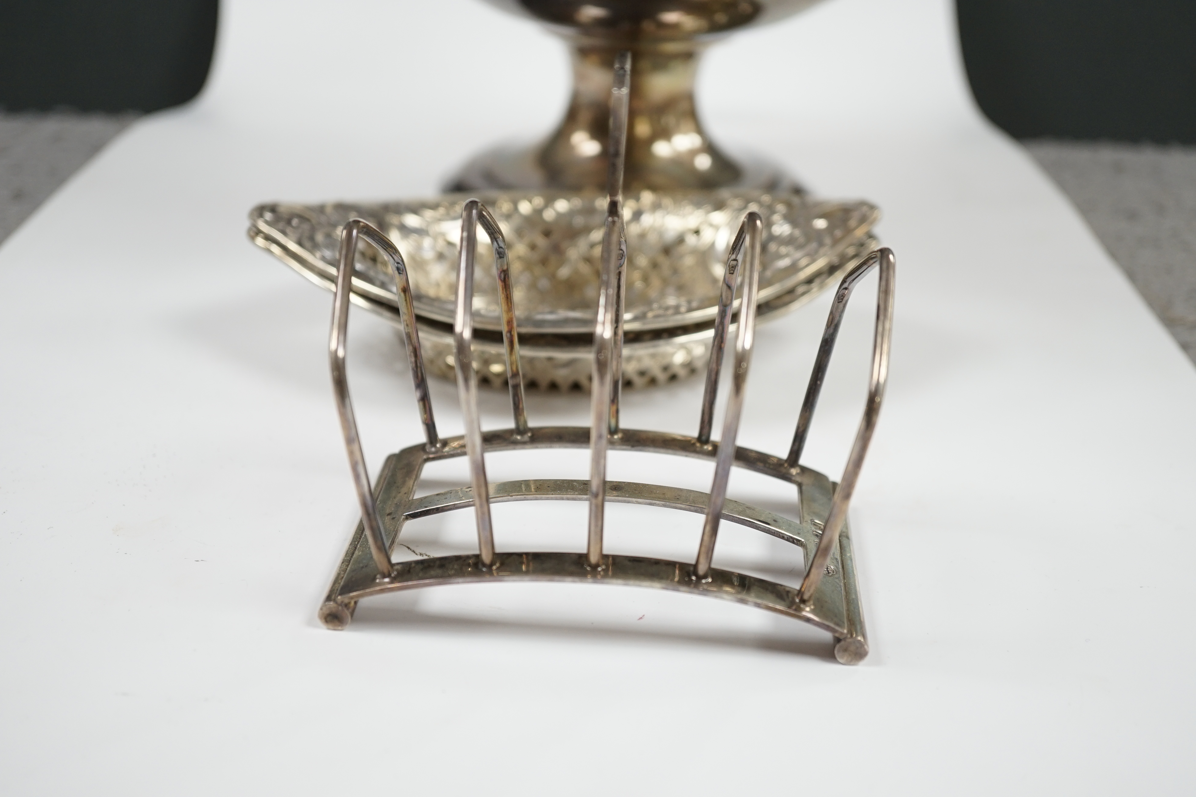 A pair of late Victorian pierced silver navette shaped bonbon dishes, 15.4cm, a silver five bar toast rack and a plated punch bowl and cover. Condition - poor to fair